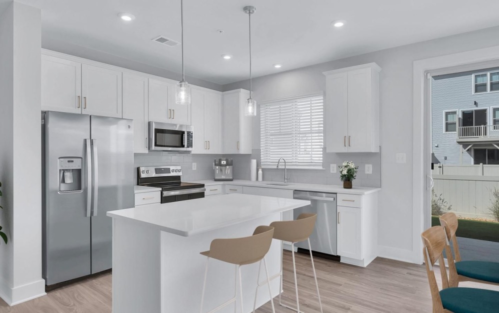 Model kitchen at Brookestone Townhomes for rent in Maryland, featuring white cabinetry and counter seating.