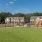 a large green field with houses in the background
