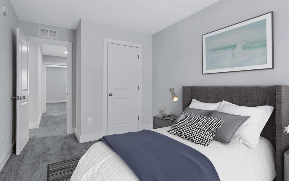 Model bedroom at our townhomes for rent in Waldorf, MD, featuring white bedspread and a view of the closet.
